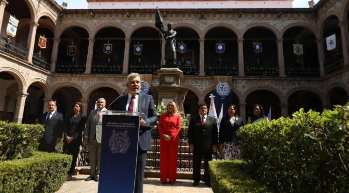 Ramírez Bedolla destaca legado de Hidalgo en la Universidad Michoacana El gobernador Alfredo Ramírez Bedolla pronuncia su discurso como orador oficial durante la ceremonia en honor a Don Miguel Hidalgo, con la rectora Yarabí Ávila y otros funcionarios escuchando atentamente.