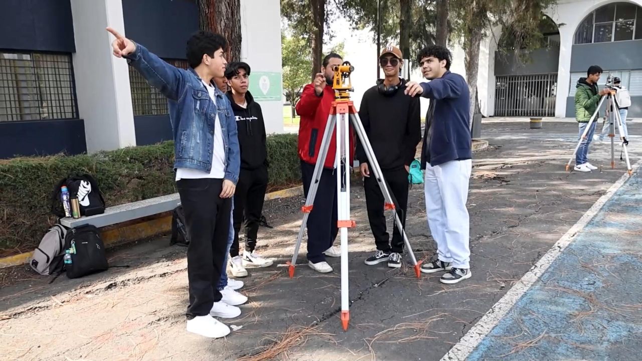 Estudiantes de Ingeniería Civil colaboran en una práctica de topografía, señalando puntos de referencia, guiados por un compañero en el uso del teodolito.Estudiantes de Ingeniería Civil con teodolito y señalando Estudiantes de Ingeniería Civil colaboran en una práctica de topografía, señalando puntos de referencia, guiados por un compañero en el uso del teodolito.Estudiantes de Ingeniería Civil con teodolito y señalando