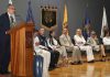UMSNH celebra quince años de su Defensoría Universitaria Dr. Jesús Santillán, Intervención institucional en el estrado, acompañada de banderas y distintivos universitarios que subrayan el carácter formal de la ceremonia.