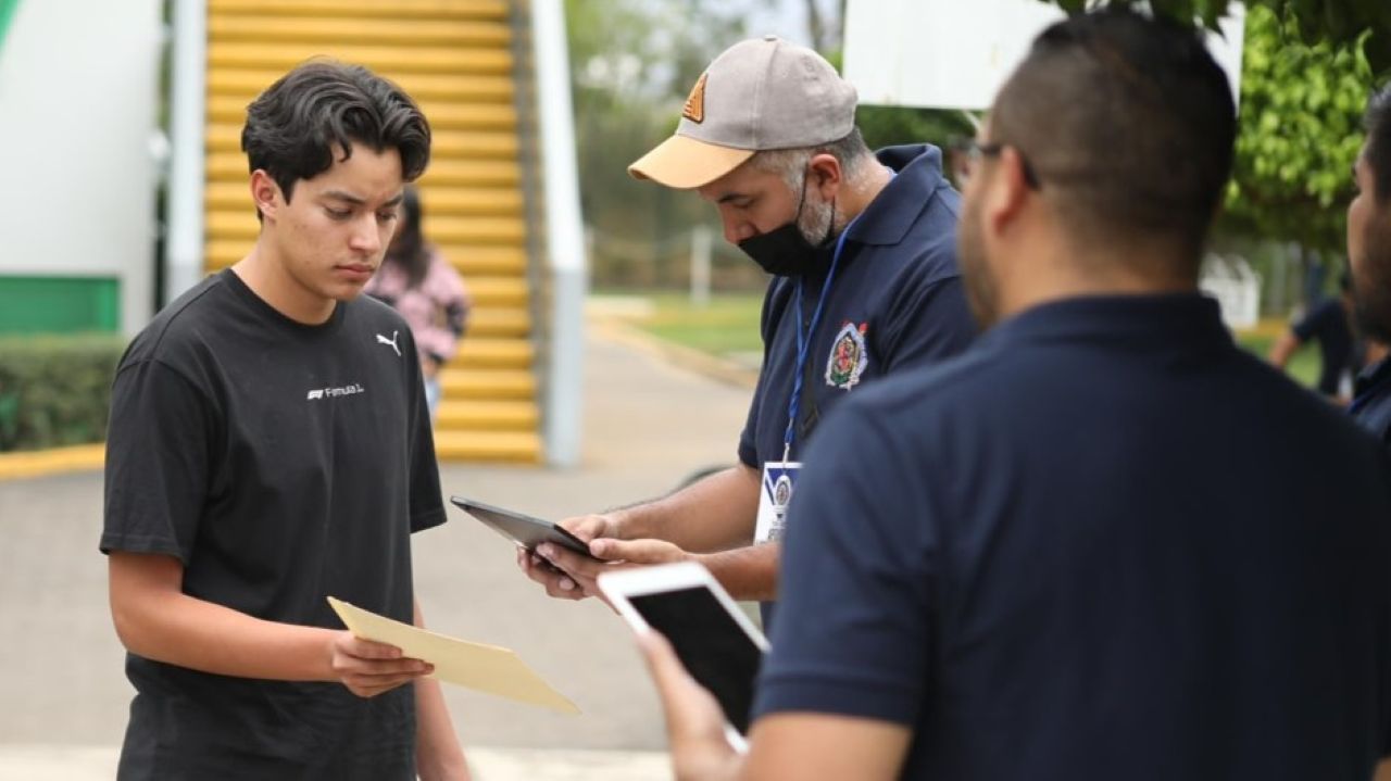 Personal institucional de la UMSNH verifica la documentación de un aspirante previo al ingreso al recinto del examen de admisión. La correcta presentación de la ficha de ingreso y la identificación oficial son requisitos que la Dirección de Control Escolar establece como obligatorios para todos los jóvenes que participan en la Convocatoria de Nuevo Ingreso 2026, cuya aplicación de exámenes inicia el martes 30 de junio. Personal institucional de la UMSNH verifica la documentación de un aspirante previo al ingreso al recinto del examen de admisión. La correcta presentación de la ficha de ingreso y la identificación oficial son requisitos que la Dirección de Control Escolar establece como obligatorios para todos los jóvenes que participan en la Convocatoria de Nuevo Ingreso 2026, cuya aplicación de exámenes inicia el martes 30 de junio.