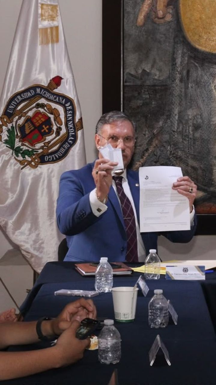 El director de la Facultad de Ciencias Médicas y Biológicas "Dr. Ignacio Chávez" Dr. Francisco Elías Vargas Merino exhibe ante las cámaras de televisión el acta notarial firmada y los empaques de seguridad que resguardaban los archivos electrónicos del examen de admisión. El director de la Facultad de Ciencias Médicas y Biológicas "Dr. Ignacio Chávez" Dr. Francisco Elías Vargas Merino exhibe ante las cámaras de televisión el acta notarial firmada y los empaques de seguridad que resguardaban los archivos electrónicos del examen de admisión.