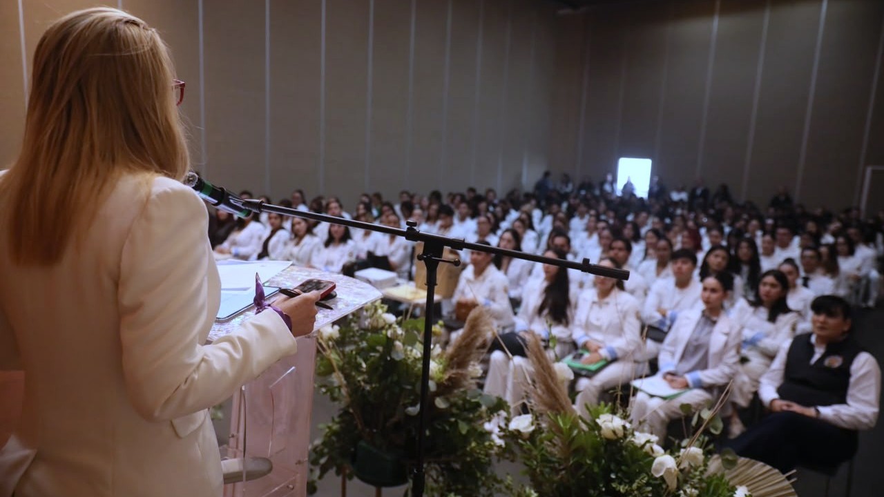 La rectora Yarabí Ávila González dirige un mensaje desde el podio a los egresados de ciencias de la salud, instándolos a conducirse con vocación humanista y compromiso social en sus campos clínicos asignados. La rectora Yarabí Ávila González dirige un mensaje desde el podio a los egresados de ciencias de la salud, instándolos a conducirse con vocación humanista y compromiso social en sus campos clínicos asignados.