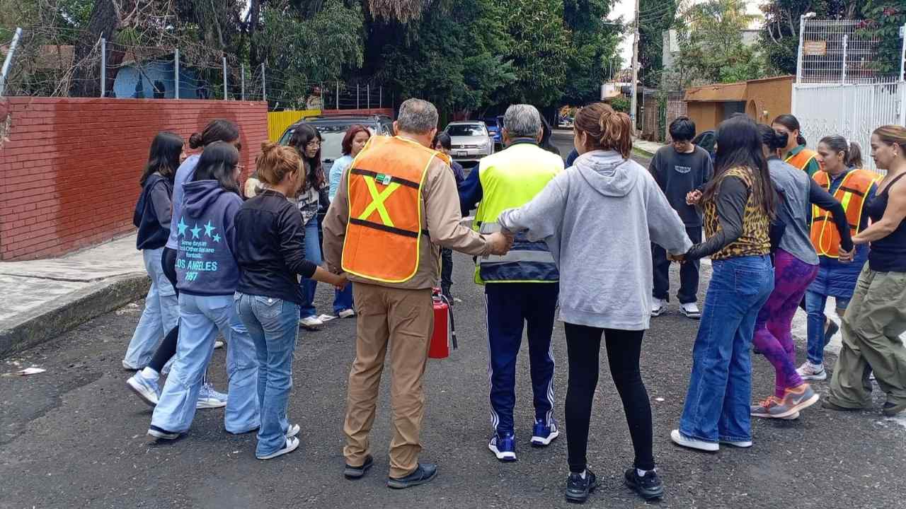 Brigadistas con chaleco de seguridad coordinan dinámica de organización con estudiantes en la vía pública, durante actividades de prevención de riesgos de la UMSNH. Brigadistas con chaleco de seguridad coordinan dinámica de organización con estudiantes en la vía pública, durante actividades de prevención de riesgos de la UMSNH.